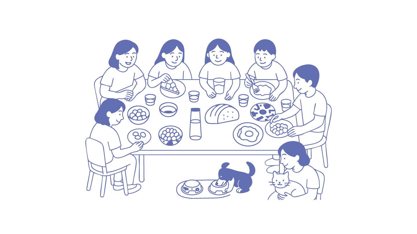 Six people share a warm meal at a dining table with pets nearby, embodying joyful cohabitation.