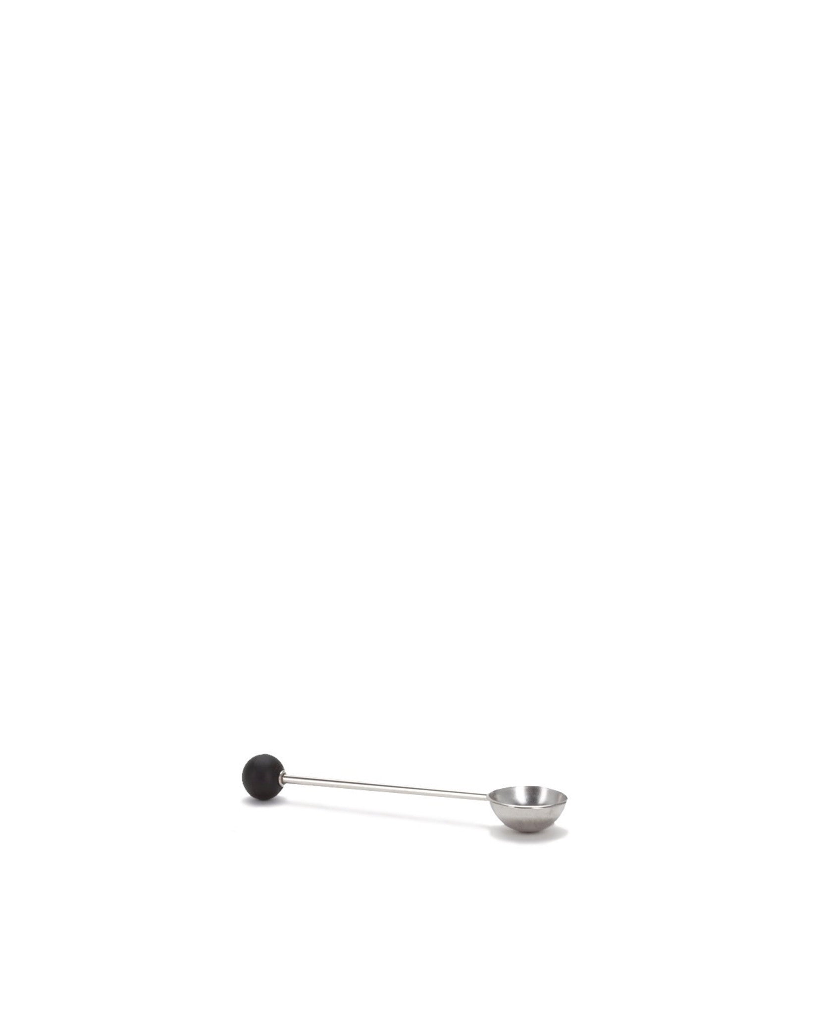 A sleek, long-handled silver measuring spoon by Alessi, with a round black ball on the handle end.